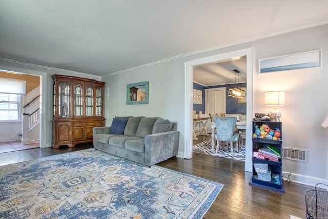 living room featuring wood finished floors, crown molding, baseboards, and stairs