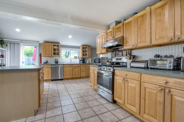 kitchen with stainless steel appliances, under cabinet range hood, light tile patterned floors, dark countertops, and recessed lighting