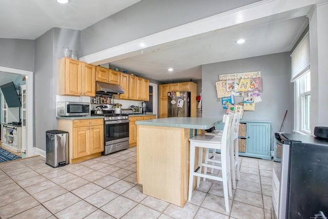 kitchen with stainless steel appliances, under cabinet range hood, light tile patterned floors, recessed lighting, and a kitchen island