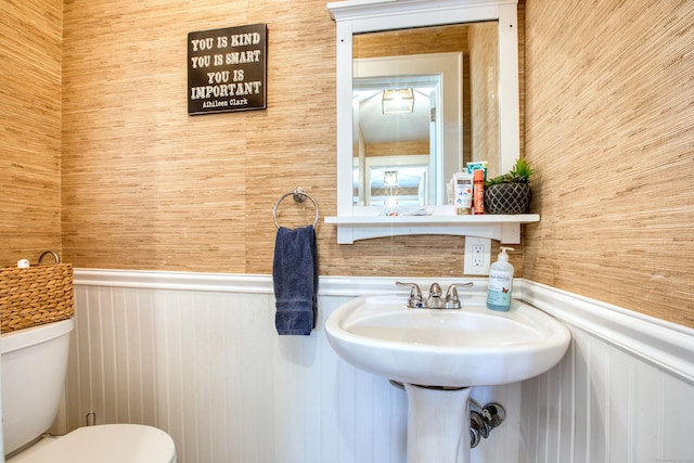 bathroom with toilet, wainscoting, and wooden walls