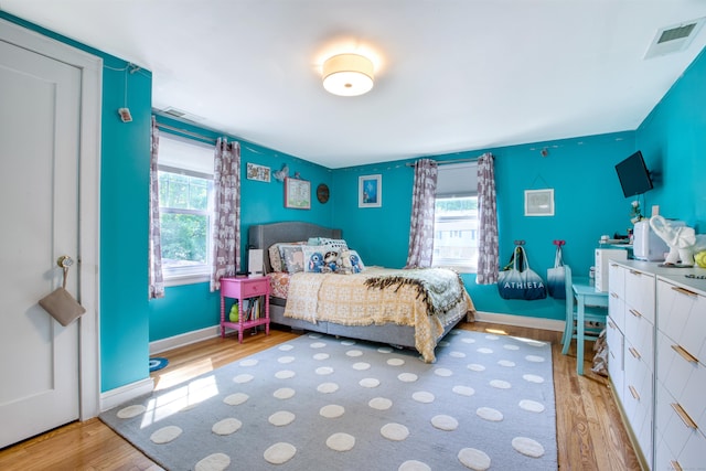 bedroom with wood finished floors, multiple windows, and baseboards