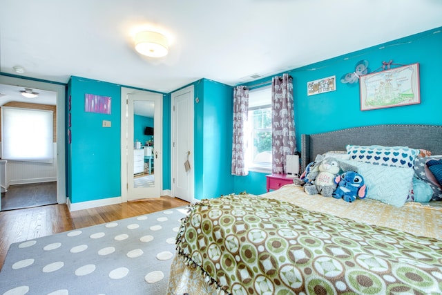bedroom with wood finished floors, a closet, and baseboards