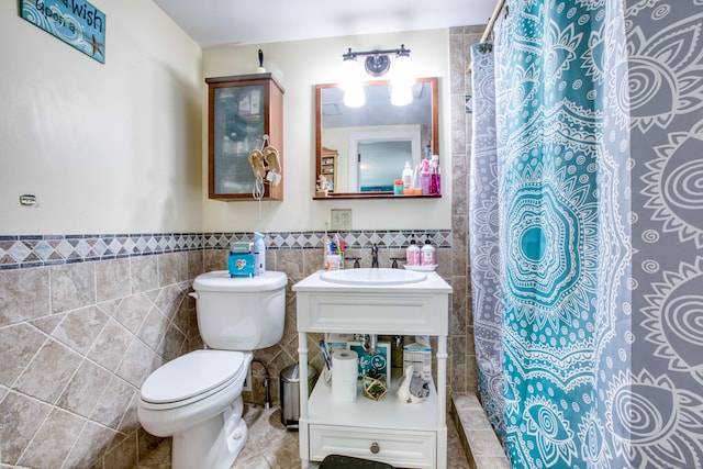 full bath featuring tile walls, a sink, toilet, a shower with curtain, and a wainscoted wall