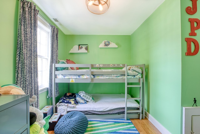 bedroom featuring multiple windows, wood finished floors, and baseboards