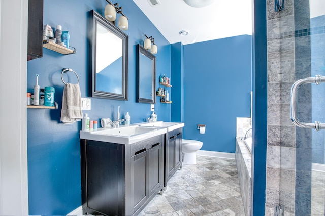 full bathroom featuring tiled shower, vanity, toilet, stone finish floors, and baseboards