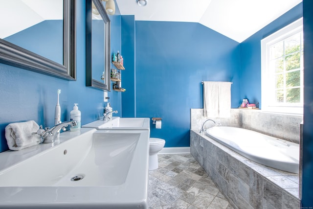 bathroom featuring stone finish flooring, a bath, vaulted ceiling, baseboards, and toilet