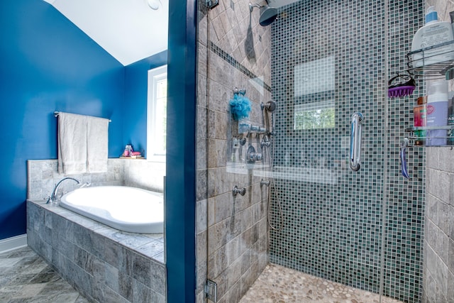 bathroom with a stall shower, a bath, vaulted ceiling, and baseboards