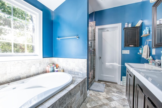 bathroom featuring healthy amount of natural light, a stall shower, a garden tub, and vanity