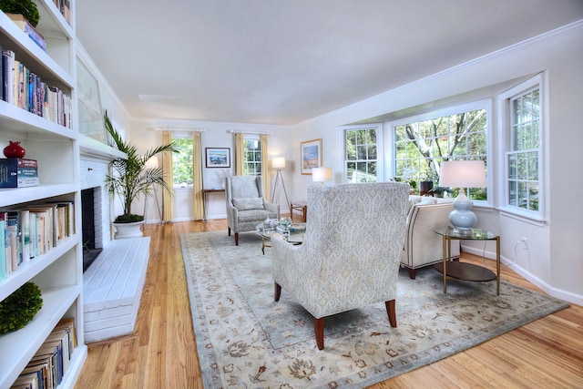 81 Grumman Hill Rd, Wilton, CT 06897 - living area featuring a brick fireplace, light wood-style flooring, baseboards, and crown molding