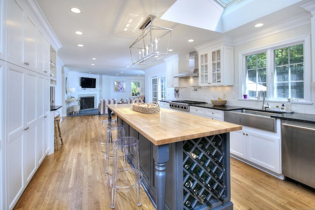 81 Grumman Hill Rd, Wilton, CT 06897 - kitchen with wooden counters, stainless steel appliances, wall chimney range hood, a sink, and white cabinets