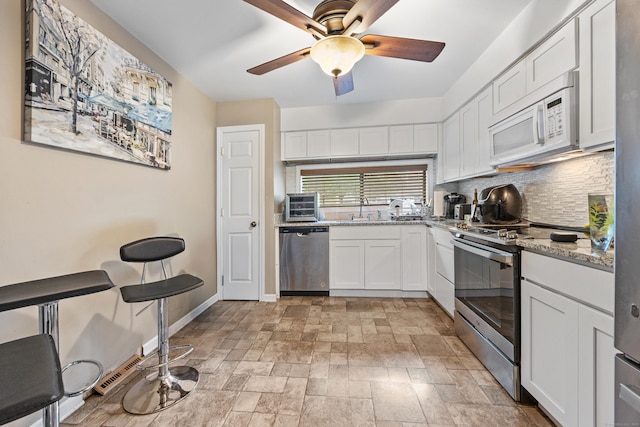 47 Currier Pl Unit 47, Cheshire, CT 06410 - kitchen featuring appliances with stainless steel finishes, tasteful backsplash, a ceiling fan, white cabinets, and light stone finish flooring