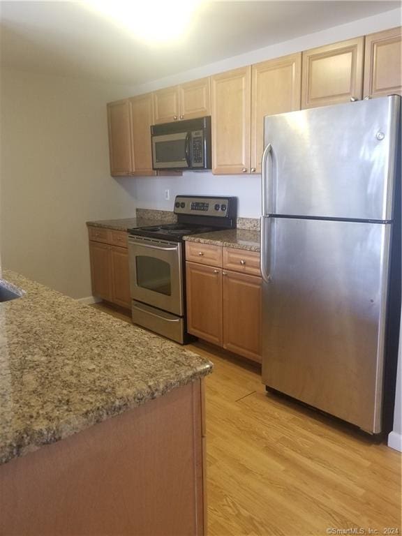 300 Broad St Unit 908, Stamford, CT 06902 - kitchen featuring stainless steel appliances, light wood finished floors, stone counters, and light brown cabinetry