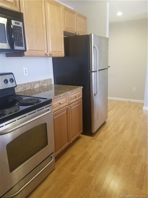 300 Broad St Unit 908, Stamford, CT 06902 - kitchen featuring appliances with stainless steel finishes, light wood-type flooring, light stone counters, light brown cabinetry, and baseboards