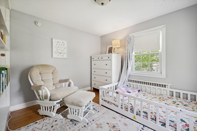 101 White Ave, West Hartford, CT 06119 - bedroom featuring radiator heating unit, wood finished floors, a crib, and baseboards