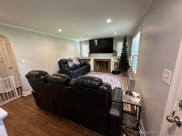 794 Center St, Manchester, CT 06040 - living room featuring arched walkways, a brick fireplace, wood finished floors, crown molding, and baseboards