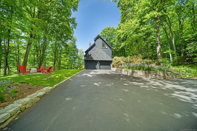 31 Poverty Hollow Rd, Newtown, CT 06470 - view of front facade featuring driveway, a garage, a front lawn, a chimney, and an outdoor fire pit