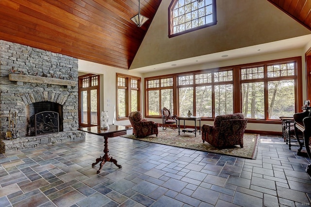 living room featuring wood ceiling, high vaulted ceiling, a fireplace, baseboards, and stone tile floors