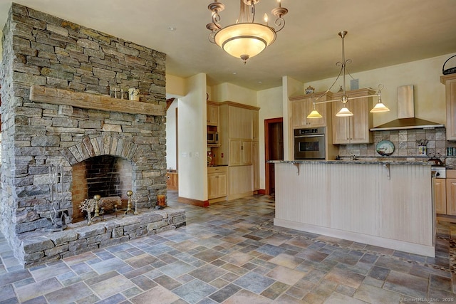 kitchen with stainless steel appliances, wall chimney range hood, stone finish flooring, a breakfast bar, and light brown cabinets