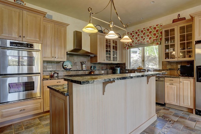 kitchen featuring stainless steel appliances, wall chimney range hood, a kitchen island, stone tile floors, and a breakfast bar