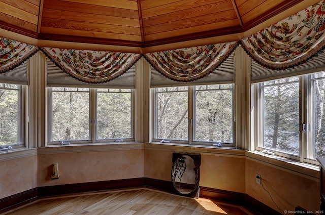 unfurnished sunroom featuring baseboards and wood finished floors