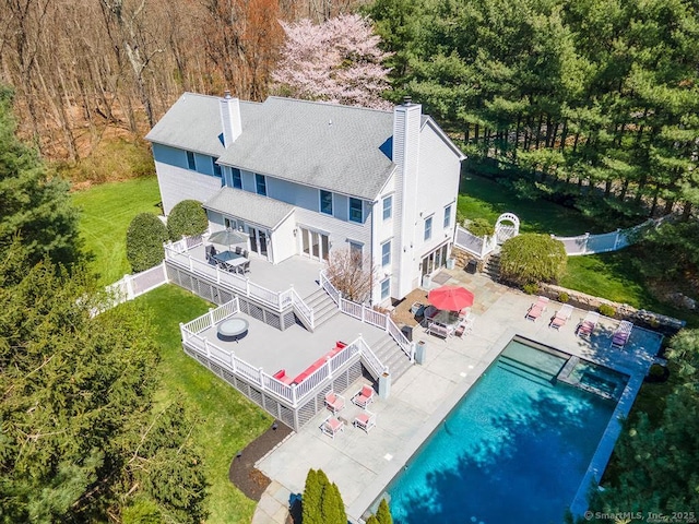 112 Old Belden Hill Rd, Norwalk, CT 06850 - rear view of house featuring a chimney, stairway, a patio area, an outdoor pool, and a view of trees