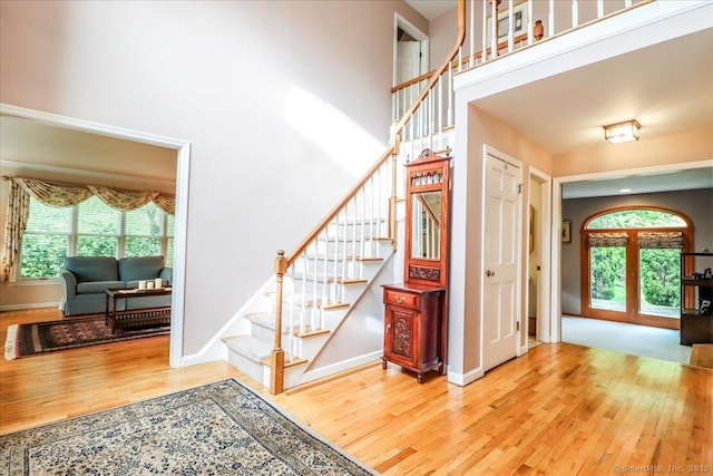 stairs featuring wood-type flooring, baseboards, and a towering ceiling