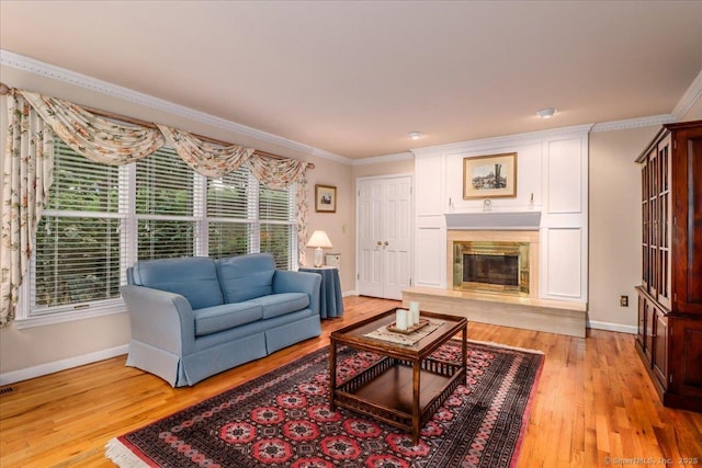 living room featuring baseboards, ornamental molding, light wood-type flooring, and a premium fireplace