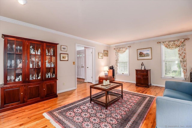living area with ornamental molding, light wood finished floors, and baseboards