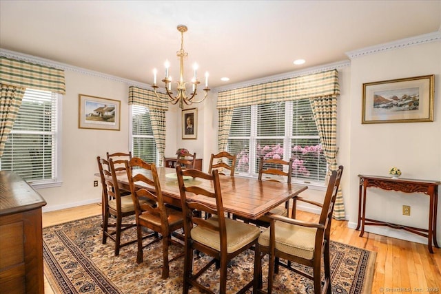 dining area featuring a chandelier, ornamental molding, light wood-style flooring, plenty of natural light, and baseboards