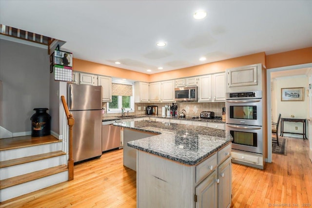kitchen with stainless steel appliances, a sink, a center island, light wood-style flooring, and recessed lighting