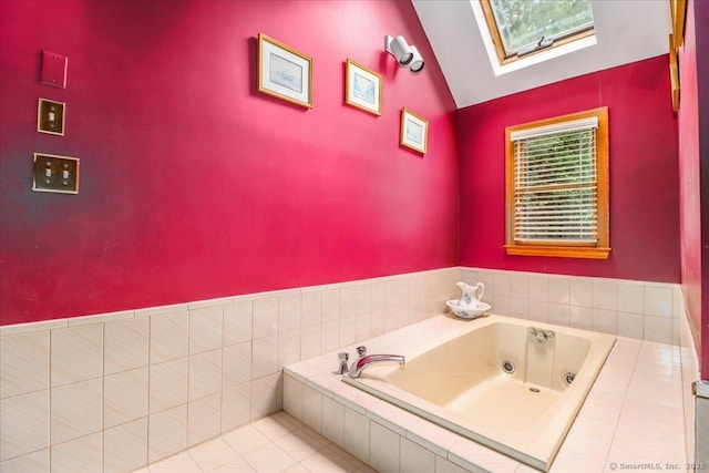 bathroom featuring vaulted ceiling, a skylight, a tub with jets, and tile patterned flooring