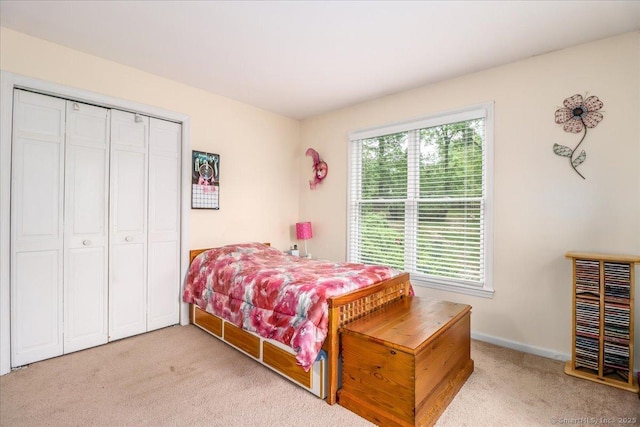 bedroom with light carpet, a closet, and baseboards