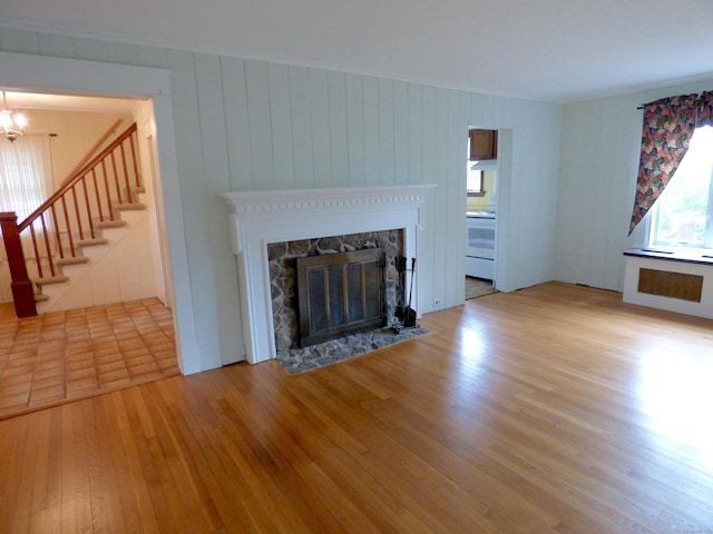 992 Ridge Rd, Wethersfield, CT 06109 - unfurnished living room featuring radiator, wood finished floors, a stone fireplace, crown molding, and stairway