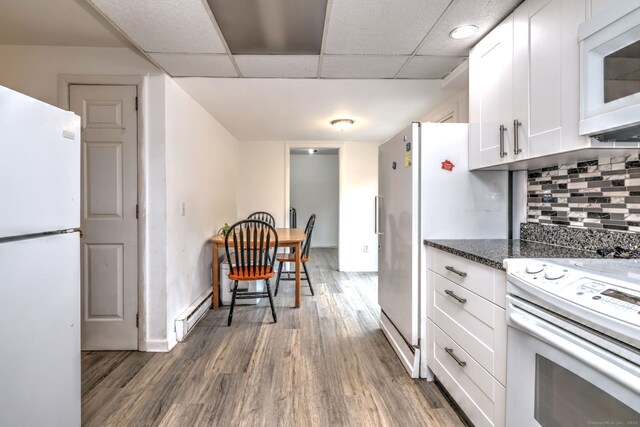 53 Harwinton Ave Apt 1, Torrington, CT 06790 - kitchen with white appliances, wood finished floors, a baseboard heating unit, white cabinets, and baseboards