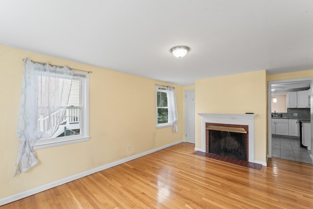 315 Prospect St, Wethersfield, CT 06109 - unfurnished living room featuring healthy amount of natural light, light wood finished floors, baseboards, and a brick fireplace