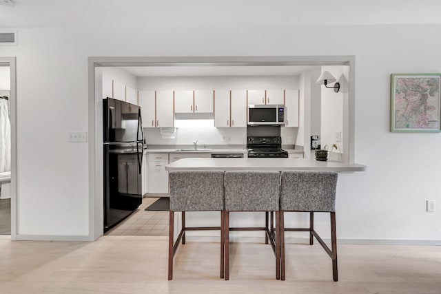 42 Temple Ct Unit 42, New Haven, CT 06511 - kitchen with black appliances, a sink, a peninsula, white cabinetry, and light countertops