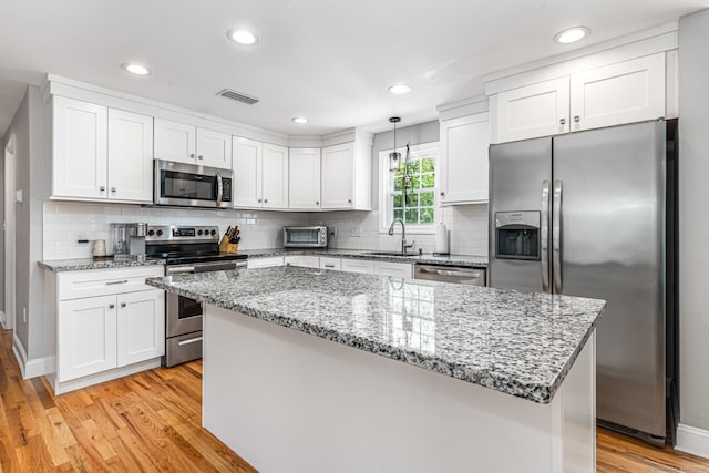 57 Harvard Ct, Middletown, CT 06457 - kitchen with appliances with stainless steel finishes, a sink, white cabinetry, light wood finished floors, and a kitchen island