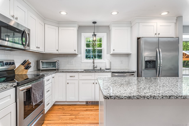 57 Harvard Ct, Middletown, CT 06457 - kitchen with appliances with stainless steel finishes, a sink, light wood finished floors, white cabinets, and pendant lighting