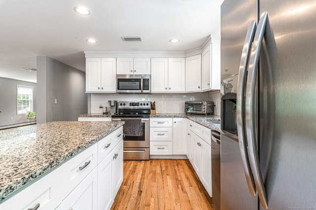 57 Harvard Ct, Middletown, CT 06457 - kitchen featuring appliances with stainless steel finishes, light wood-style floors, white cabinets, decorative backsplash, and recessed lighting