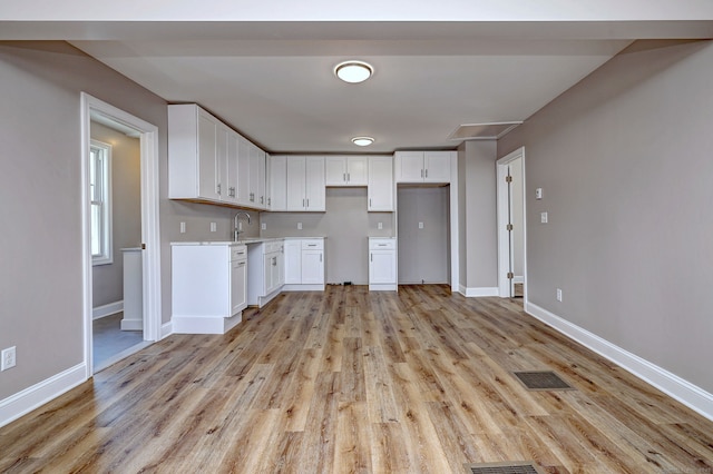 167 Gilbert St, West Haven, CT 06516 - kitchen featuring white cabinets, light wood finished floors, baseboards, light countertops, and a sink