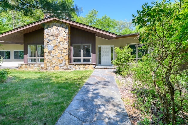 97 W Rd, Marlborough, CT 06447 - view of exterior entry with stone siding, a chimney, and a lawn