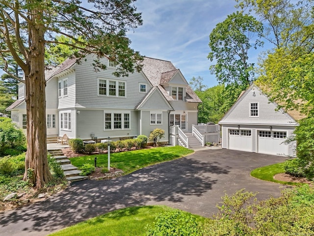 shingle-style home featuring a detached garage and stairway