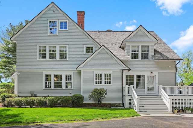 shingle-style home featuring a wooden deck, a chimney, and a front yard