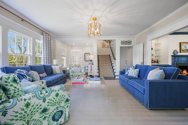 carpeted living room featuring stairway, a chandelier, crown molding, and a lit fireplace