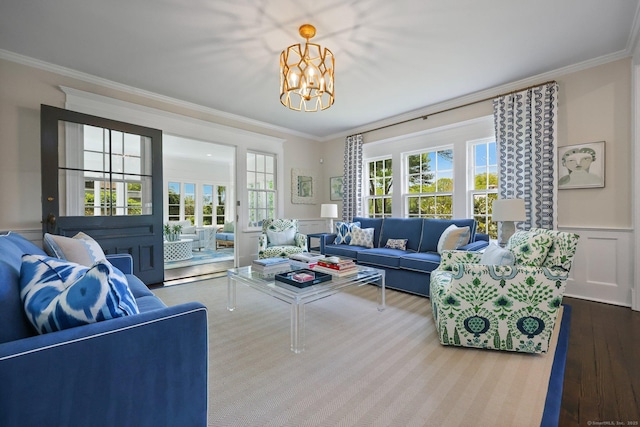 living area featuring ornamental molding, wood finished floors, a chandelier, and a wainscoted wall
