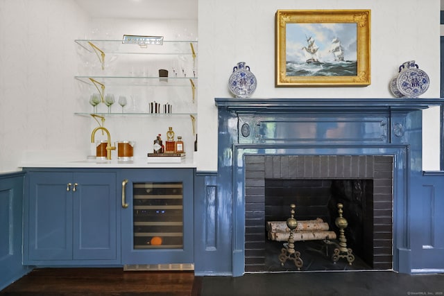 indoor wet bar featuring wine cooler, dark wood-style floors, and a brick fireplace