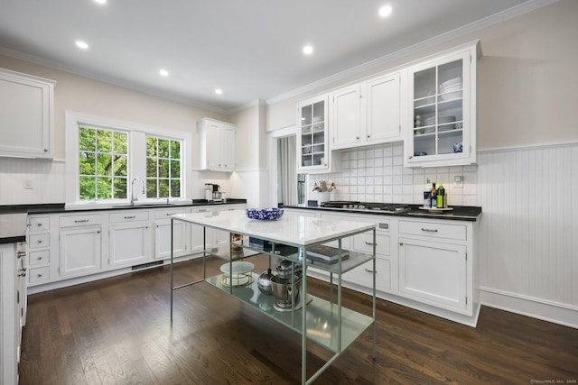 kitchen with a sink, white cabinets, ornamental molding, dark wood-type flooring, and tasteful backsplash
