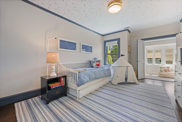 bedroom featuring wood finished floors, crown molding, and baseboards