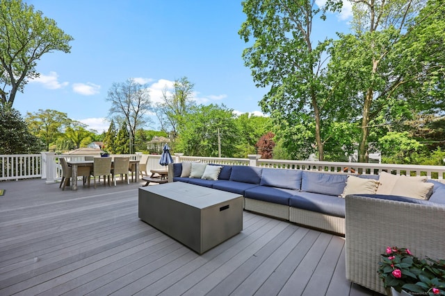 wooden deck featuring an outdoor living space, outdoor dining area, and view of scattered trees