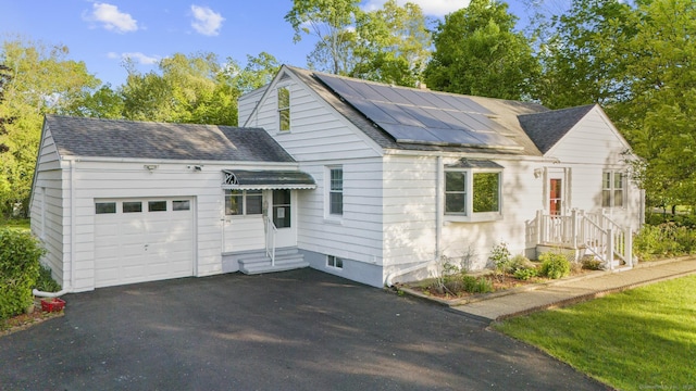 130 Fitch St, North Haven, CT 06473 - view of front of home with an attached garage, roof with shingles, asphalt driveway, and solar panels